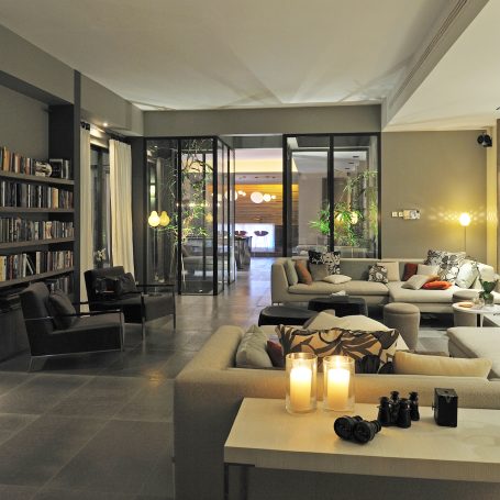 Intérieur moderne d'un salon avec des canapés, des livres et des bougies allumées.