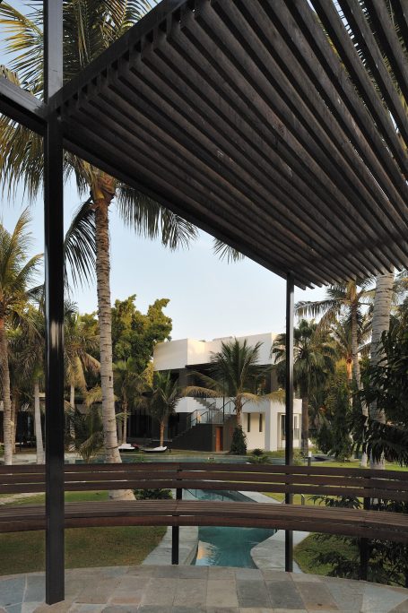 Structure moderne avec auvent, vue sur une piscine et un jardin tropical.