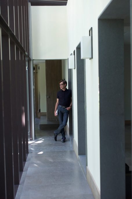 Homme marchant dans un couloir moderne et lumineux avec des murs clairs.