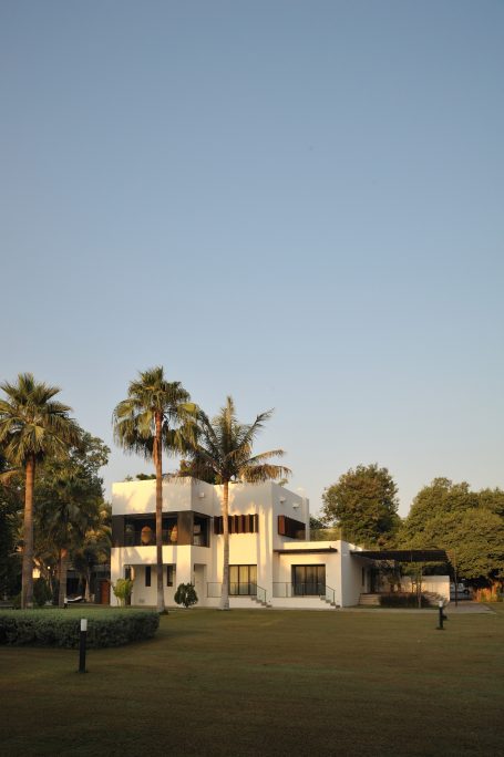 Maison moderne entourée de palmiers, avec un ciel dégagé en arrière-plan.